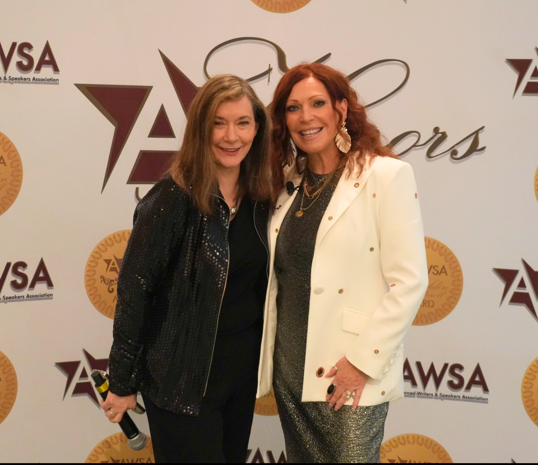 Two women posing in front of the AWSA Golden Scrolls backdrop