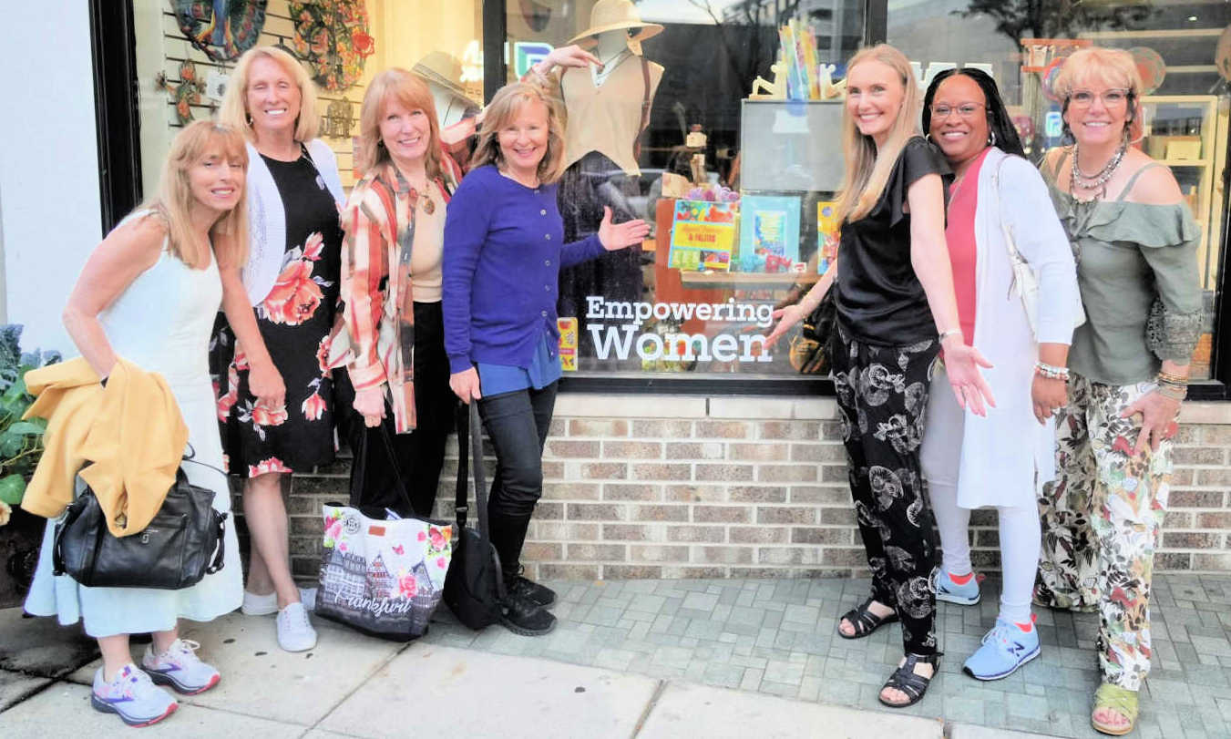 Seven AWSA members posing together in front of an Empowering Women storefront