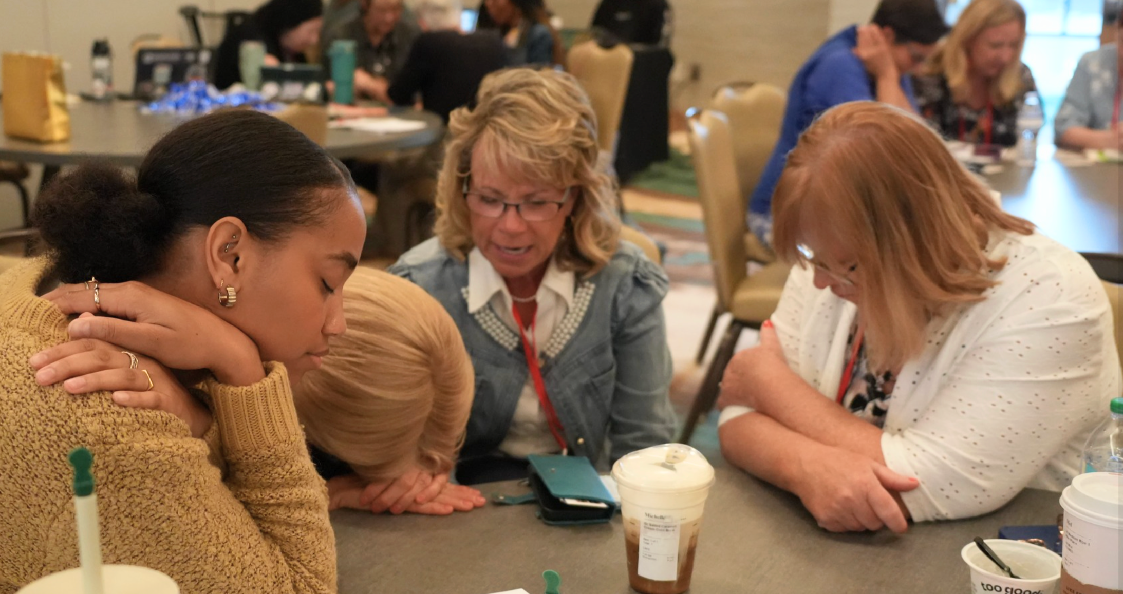 Small group bowing in prayer at a table