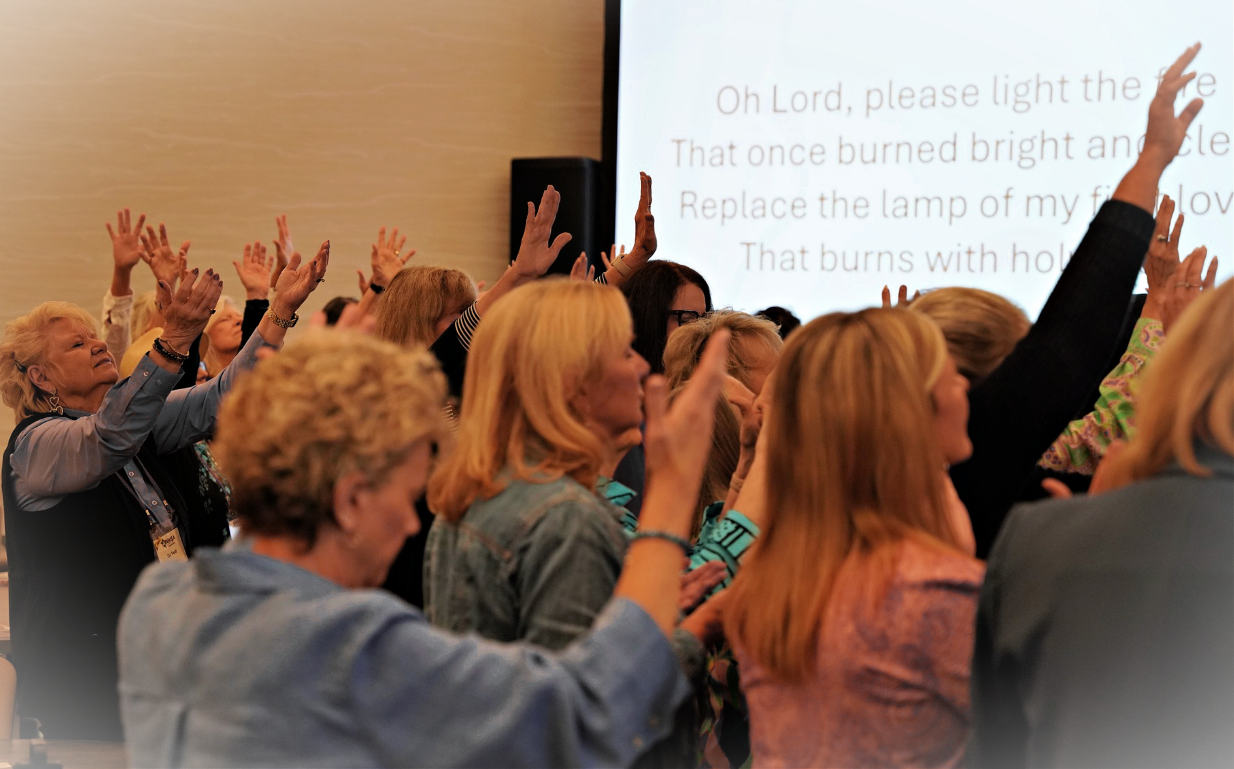 Hands raised in worship as the screen displays the lyrics of Refiners Fire
